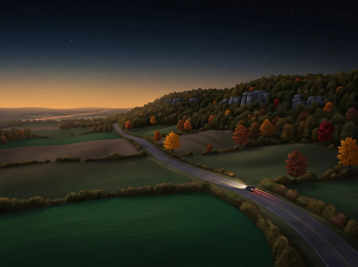 Rolling Niagara Escarpment countryside at dusk, a two-lane country road winding between fields and limestone-edged woods